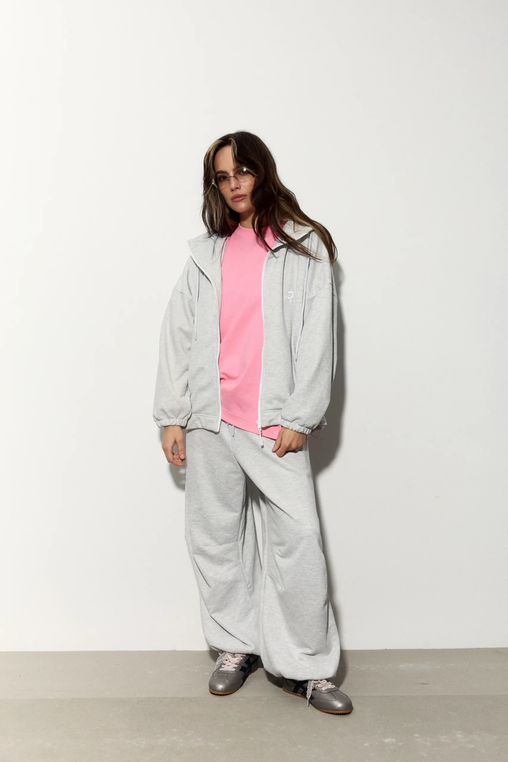Жіноче oversized худі сірого кольору з футеру діагональ преміум. Вільний силует, блискавка та м’яка фактура для casual образів. - romanova4895_Original Худі жіноче oversized сіре на блискавці без утеплення - Person modeling casual athleisure: pink t-shirt under a gray zip-up hoodie and matching gray sweatpants, standing against a light background.
