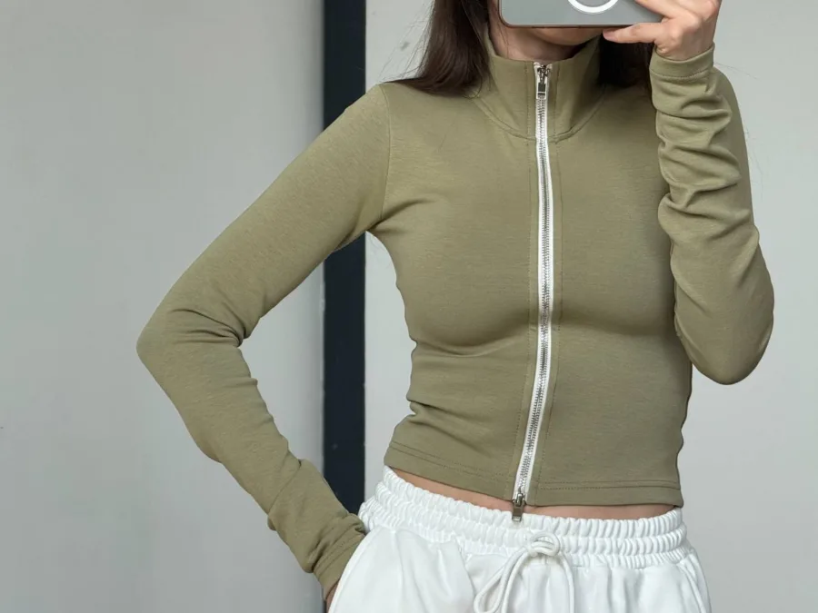 Жіноча сорочка в червону клітинку one size - Cropped olive-green zip-up long-sleeve top with a silver zipper, paired with white drawstring shorts in a fashion pose.