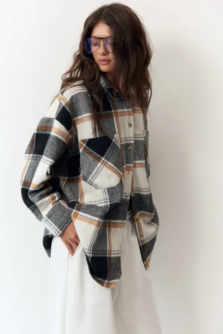 Сукня жіноча кімоно міні графіт модал 85% вільний силует - Casual fashion shot: a model wearing an oversized plaid flannel shirt in neutral tones with white pants and blue-tinted sunglasses, posing against a white background.
