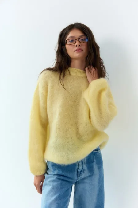 Светр жіночий оливковий бавовняний one size - Woman wearing a pale yellow fuzzy sweater and blue jeans, posing against a white wall.